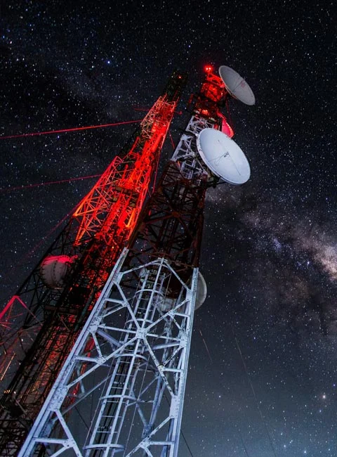 Två telemaster med paraboler och röd belysning mot en stjärnklar natthimmel.